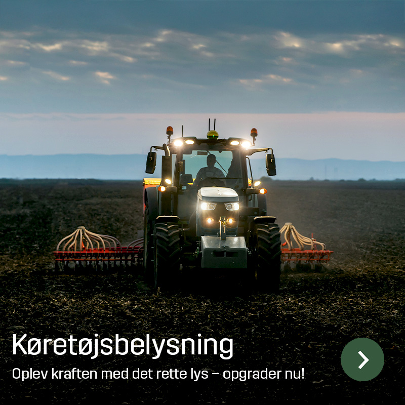 Traktor med tændt arbejdsbelysning kører på marken med et bredt redskab bagpå. Sagros køretøjsbelysning giver lys omkring landbrugsmaskiner under arbejde i marken.